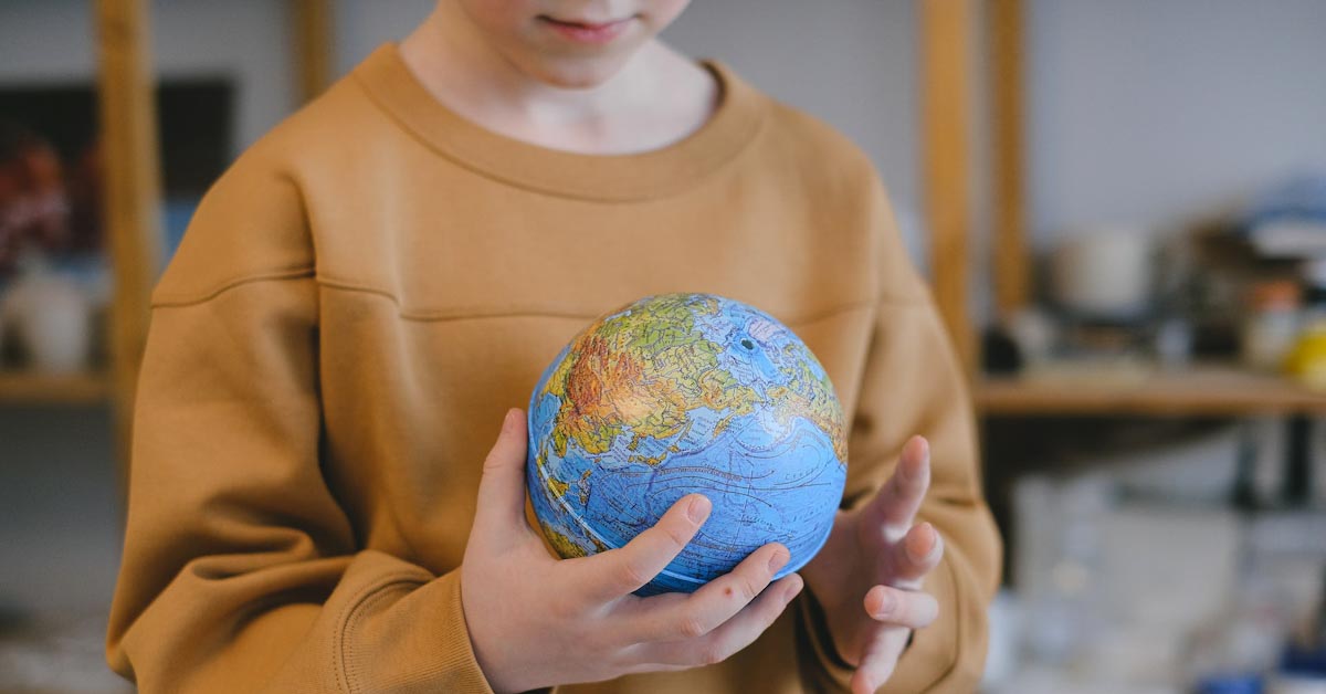 Een hoogbegaafd kind in de leeftijd basisschool met een kleine globe in zijn handen.